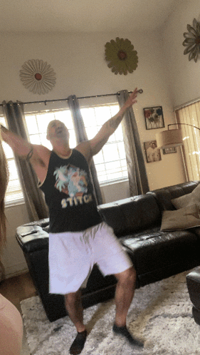 A Man Dancing In A Living Room With A Stitch Shirt On GIF