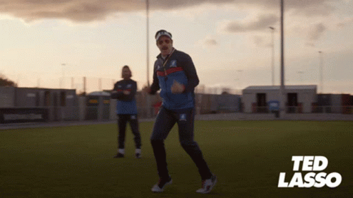 A Man Dancing On A Field With The Name Ted Lasso In The Corner GIF