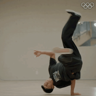 A Man Doing A Handstand In Front Of A Mirror With The Olympic Rings In The Background GIF