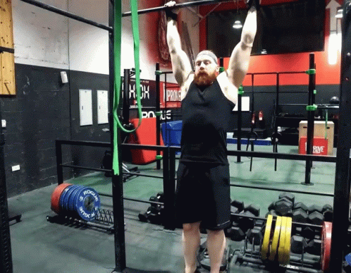 A Man Doing A Pull Up In A Gym With A Sign That Says Prime GIF