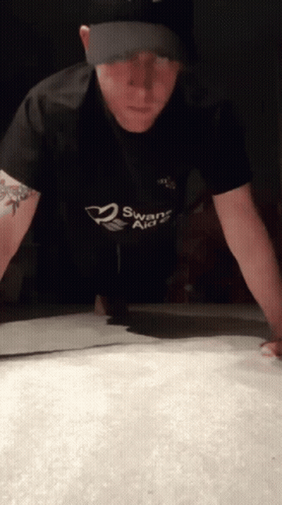 A Man Doing Push Ups With A Swans Aid Shirt On GIF