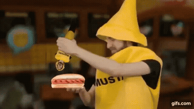 A Man Dressed As A Banana Is Holding A Hot Dog And Mustard . GIF