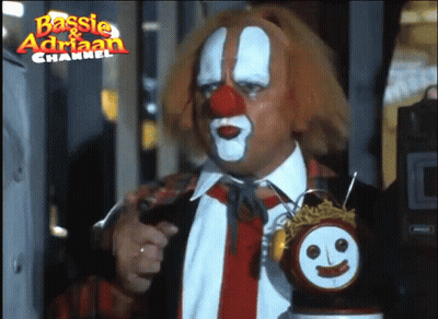 A Man Dressed As A Clown Is Holding A Clock With A Face On It And The Words Basisie & Adrian Channel Above Him GIF