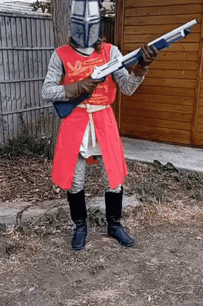 A Man Dressed As A Knight Holding A Shotgun GIF