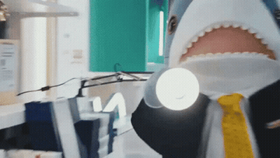 A Man Dressed As A Shark Is Holding A Flashlight GIF