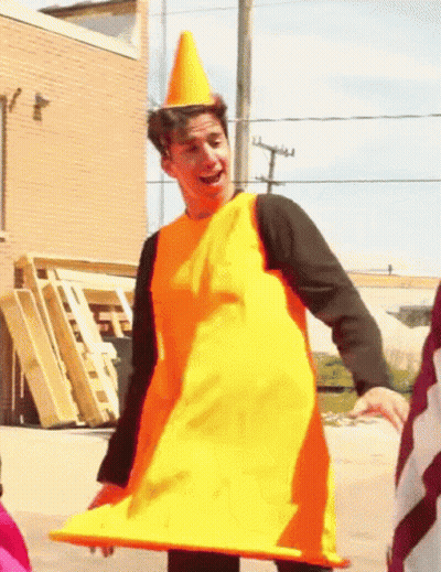 A Man Dressed As A Traffic Cone Is Smiling GIF