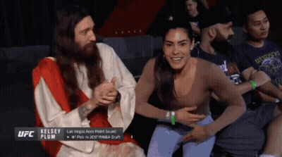 A Man Dressed As Jesus Is Sitting Next To A Woman Who Is Smiling GIF