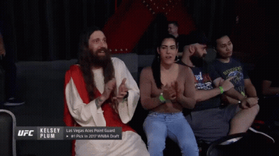 A Man Dressed As Jesus Talks To A Woman In A Crowd GIF