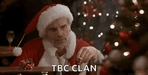 A Man Dressed As Santa Claus Is Sitting At A Table Smoking A Cigarette In Front Of A Christmas Tree . GIF