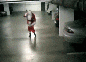 A Man Dressed As Santa Claus Is Standing In A Parking Garage GIF