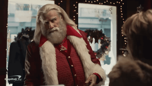 A Man Dressed As Santa Claus With A Capital One Logo On The Bottom Right GIF
