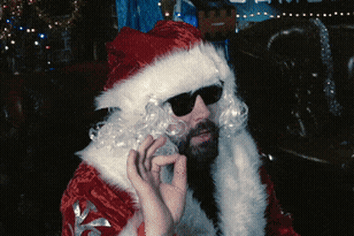 A Man Dressed As Santa Claus With Sunglasses And A Beard GIF