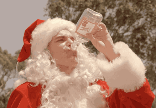 A Man Dressed As Santa Drinking From A Bottle GIF