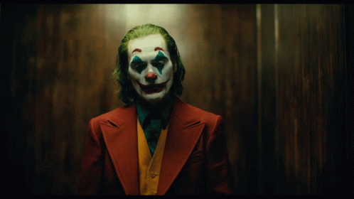 A Man Dressed As The Joker With A Clown Face And Green Hair GIF