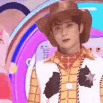 A Man Dressed As Woody From Toy Story Is Standing In Front Of A Purple Background . GIF