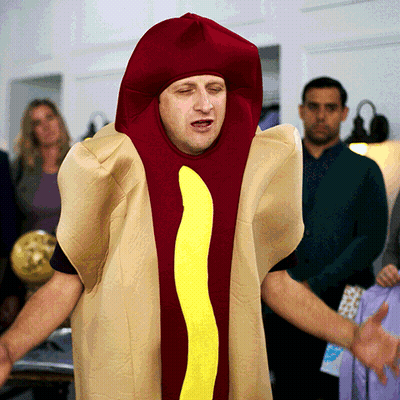A Man Dressed In A Hot Dog Costume With A Yellow Sausage GIF