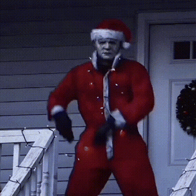 A Man Dressed In A Santa Suit Is Standing On A Porch GIF