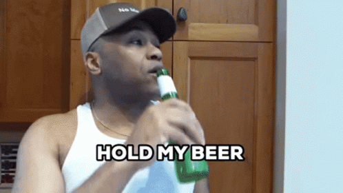 A Man Drinking A Bottle Of Beer With The Words Hold My Beer Behind Him GIF