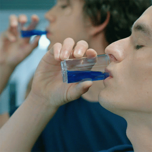 A Man Drinking A Shot Of Blue Liquid From A Glass GIF