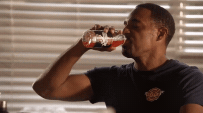 A Man Drinking From A Bottle That Says Firefighter GIF