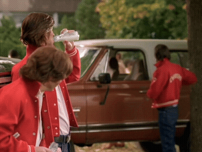 A Man Drinking From A Bottle While Wearing A Red Jacket That Says ' Columbia ' On It GIF
