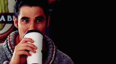A Man Drinking From A Cup With A Sign Behind Him That Says A Be GIF