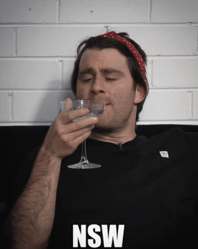 A Man Drinking From A Glass With The Word Nsw On The Bottom Right GIF