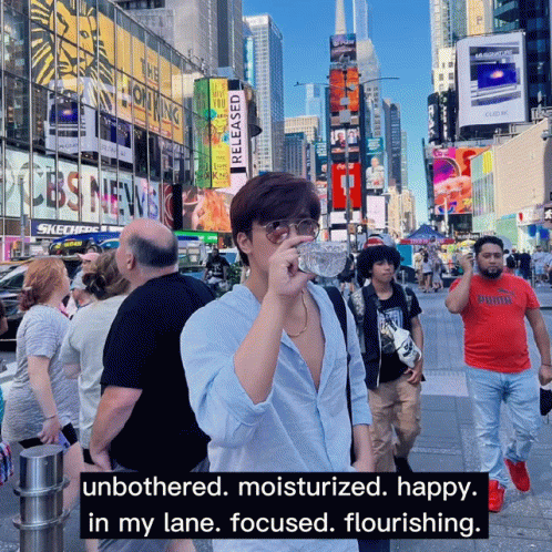 A Man Drinking Water From A Bottle In A Crowded City GIF