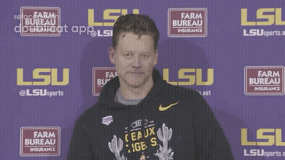 A Man Drinks From A Bottle In Front Of A Sign That Says Farm Bureau GIF