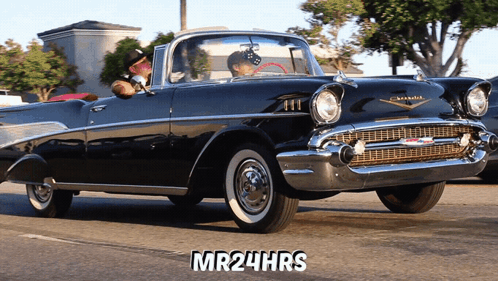 A Man Driving A Black Chevrolet With The Words Mr24hrs On The Bottom GIF