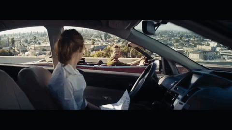 A Man Driving A Red Convertible With A Woman Sitting In The Back Seat GIF