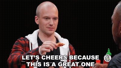 A Man Eating A Chicken Wing With The Words Let 'S Cheers Because This Is A Great One Above Him GIF