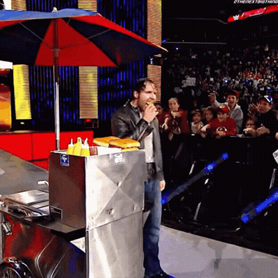 A Man Eating A Hot Dog In Front Of A Crowd That Says The Next Thing GIF