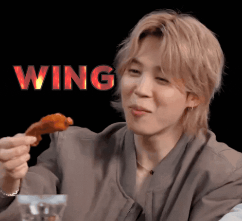 A Man Eating A Piece Of Chicken With The Word Wing Above Him GIF