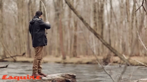 A Man Fishing In A River With The Word Esquire On The Bottom Right GIF