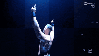 A Man Flexes His Muscles In Front Of A Screen That Says Tnt Sports GIF