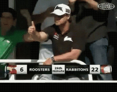 A Man Gives A Thumbs Up In Front Of A Scoreboard That Says Roosters 26Th Minute Rabbitohs 22 GIF