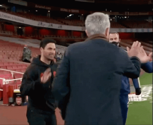 A Man Giving A High Five To Another Man In A Stadium GIF