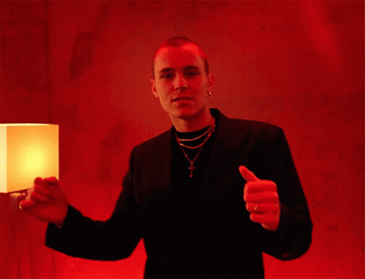 A Man Giving A Thumbs Up In Front Of A Lamp GIF