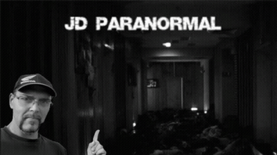 A Man Giving A Thumbs Up In Front Of A Sign That Says Paranormal GIF