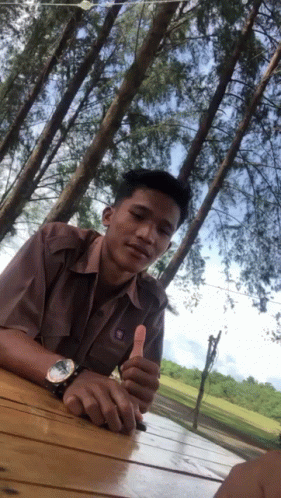 A Man Giving A Thumbs Up In Front Of Trees GIF