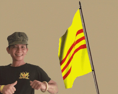 A Man Giving A Thumbs Up Next To A Flag With Red Stripes GIF