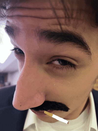 A Man Has A Fake Mustache And A Cigarette In His Mouth GIF