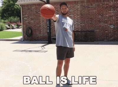A Man Holding A Basketball In Front Of A Brick Building With The Words " Ball Is Life " Below Him GIF