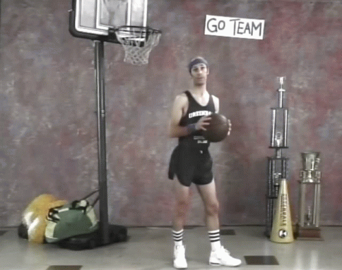 A Man Holding A Basketball In Front Of A Go Team Sign GIF