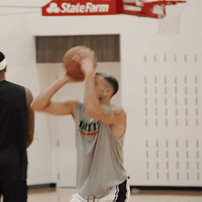 A Man Holding A Basketball In Front Of A Sign For State Farm GIF
