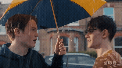 A Man Holding A Blue And Yellow Umbrella With Netflix Written On The Bottom GIF