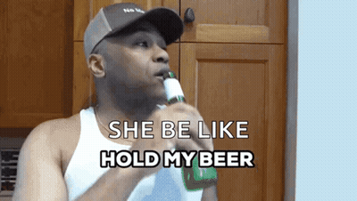 A Man Holding A Bottle Of Beer With The Words She Be Like Hold My Beer Below Him GIF