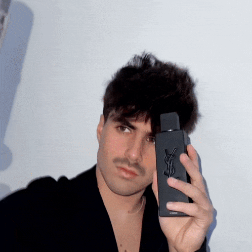 A Man Holding A Bottle Of Yves Saint Laurent Cologne GIF
