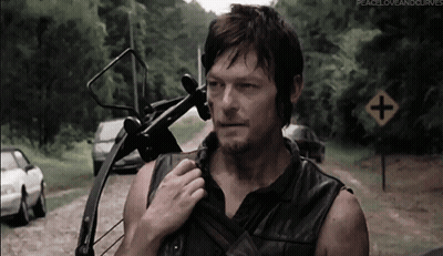 A Man Holding A Bow And Arrow Stands In Front Of A Road Sign That Says Peace Love And Curves GIF